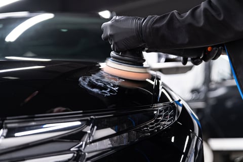 Worker removing scratches on car varnish with electric polisher