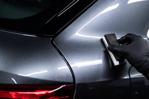 Car detailing worker applying ceramic coating on silver car body