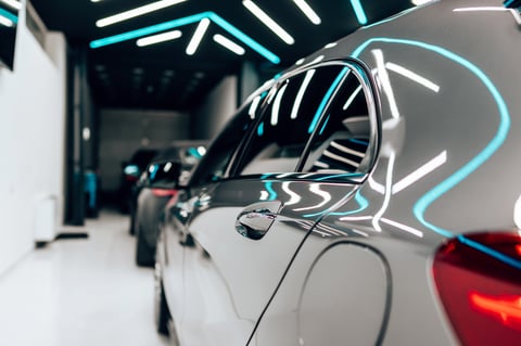 Professional vehicle polishing and detailing inside a modern car workshop with buffer tool