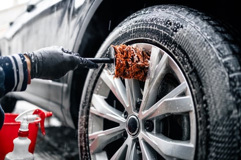 Close up of car wheel being washed with brush and soap