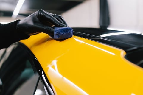 Applying ceramic coating to sports car surface with applicator during detailing