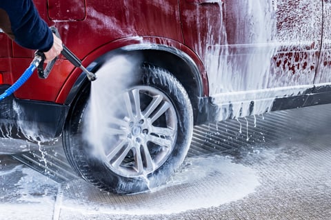Washing red car with lots of foam